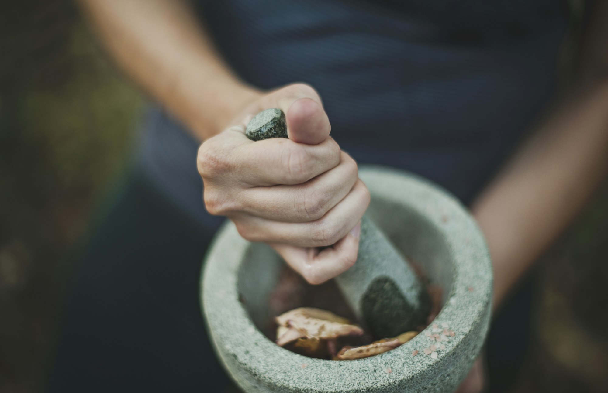Hands grinding herbs in a stone mortar