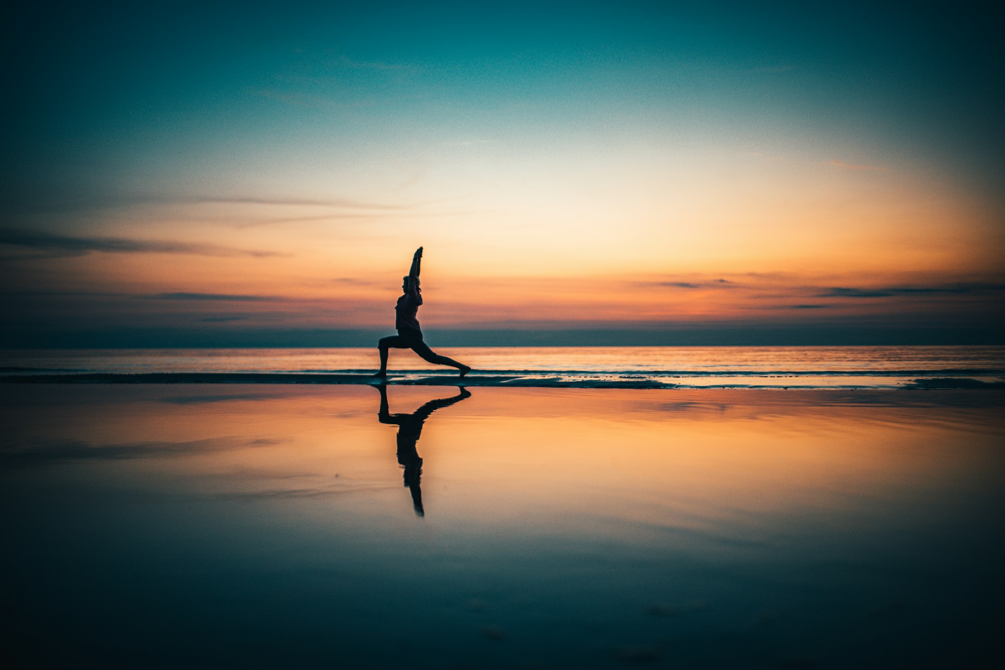 Yoga pose silhouette at sunrise by the sea